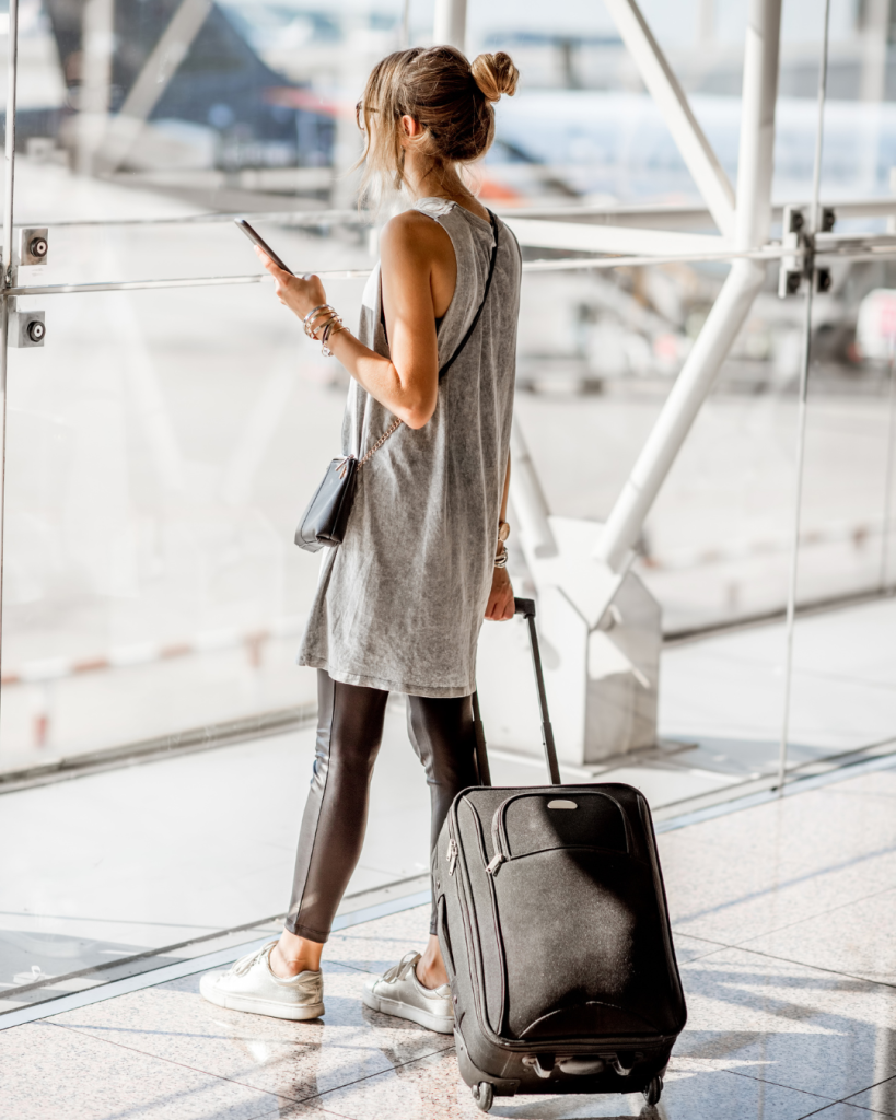 woman looking at phjone while waiting on an airport. Many women have to travel to other states looking for healthcare providers that can proceed with an abortion.