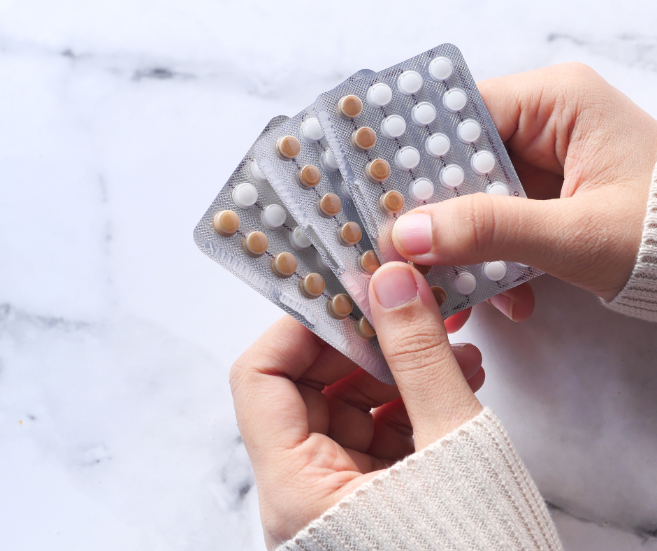 Persona sosteniendo varios blísters de pastillas anticonceptivas de diferentes colores.